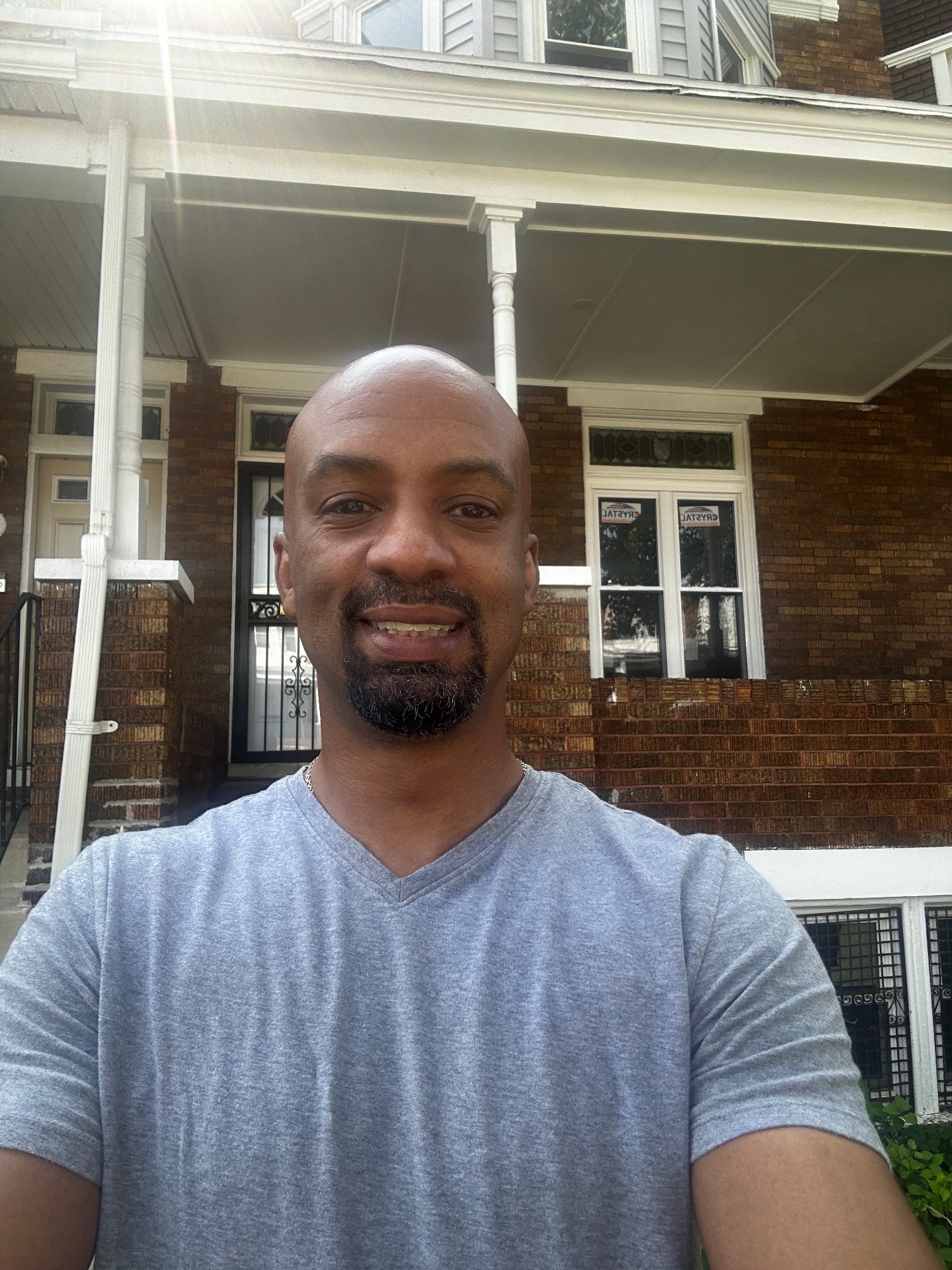 Thomas Collins, founder of ShiftRich Academy, standing in front of a brick duplex he house hacked